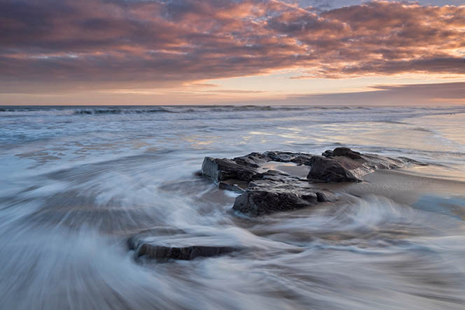 Water swirling around a rock on Cheswick Sands beach, Northumberland